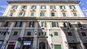 A multi-story building with a classic architectural style, featuring a ground-level pharmacy and a visible clock. - Raibetta Apartment by Wonderful Italy (Genoa)