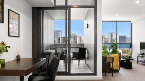 Eine moderne Wohnung mit Essbereich, einem Balkon mit Stadtblick und einem Wohnraum mit Sofa und Pflanzen.