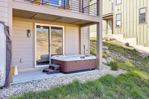 A modern outdoor hot tub area with a sliding glass door, a small table, and a step stool. - Deer Springs 4BR | Private Hot Tub | Deer Valley & Jordanelle Views (Hideout)