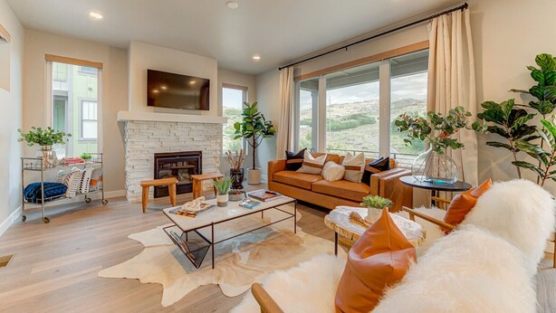 Amplia sala de estar con chimenea, sofá, mesa de centro y ventanas grandes que ofrecen vistas al exterior.