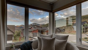 Una habitación acogedora con un ventanal grande que da a una zona residencial, un sofá cómodo y una mesita con una planta.