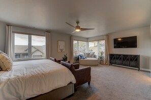 A spacious bedroom with a large bed, a seating area, and a TV mounted on the wall. - Minutes Outside of Park City (Hideout)