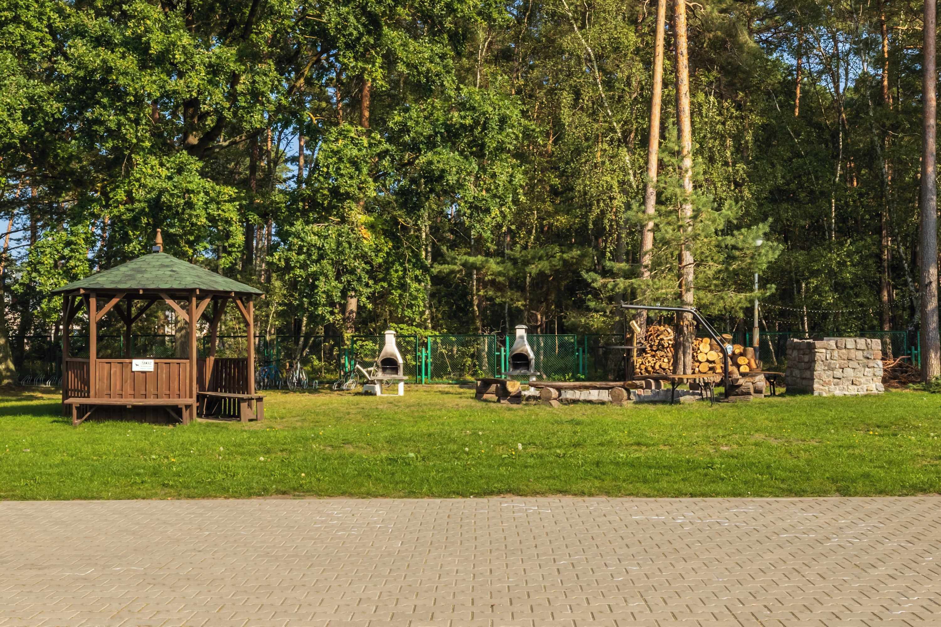 Ein Park mit einer Laube, Bänken und Außenöfen.