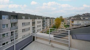 A multi-story residential building with balconies, a clear sky, and a distant view of other buildings. - Cozy Studio in Quiet Neighborhood | Balcony, Parking (Wrocław)