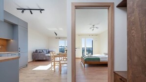 A modern interior with a kitchen, dining area, and a bedroom with a large window.