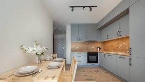 A modern kitchen with grey cabinets, a wooden countertop, and a dining area with a wooden table and chairs.