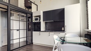 Eine moderne Küche mit einem Glastisch und weißen Stühlen, einer Mikrowelle und einem schwarzen Backofen.