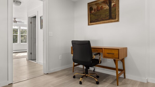 A room with a wooden desk, black office chair, and a painting on the wall. - Timeless 4-BR Farmhouse | 3 Min to Okemo (Ludlow)