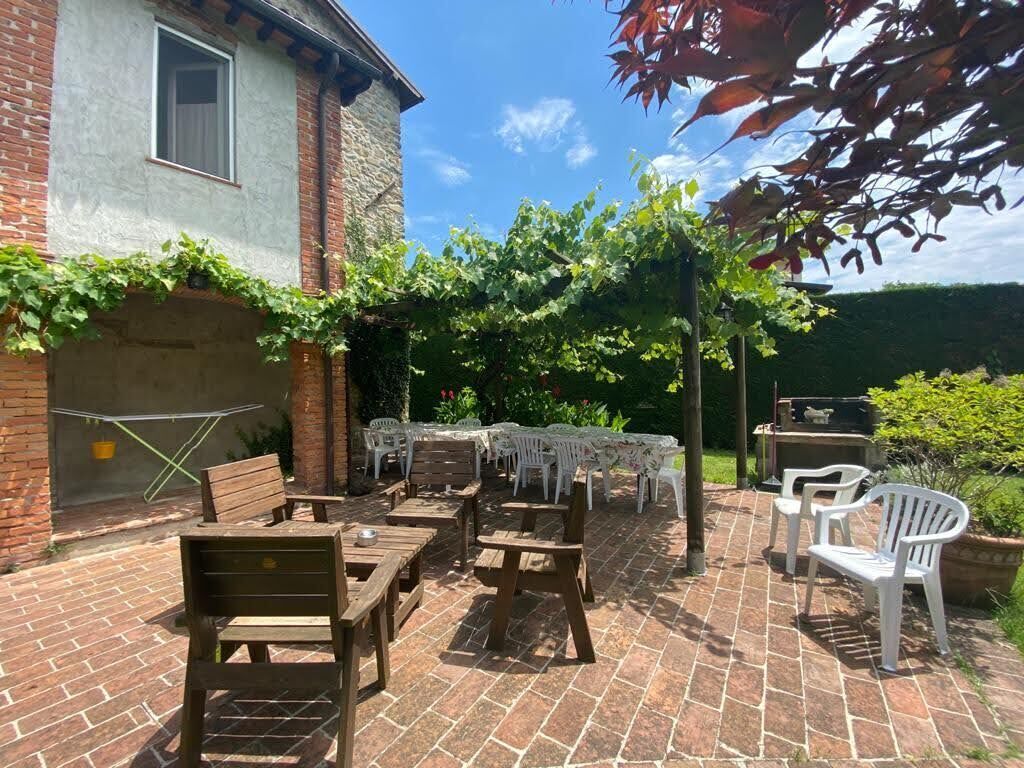 An outdoor patio with wooden tables and chairs, a white tablecloth-covered table, and a brick wall.