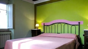 A room with a bed, a nightstand with a lamp, and a radiator. - Farmhouse with Farm in the hills of Barga: Casa Chioi (barga)