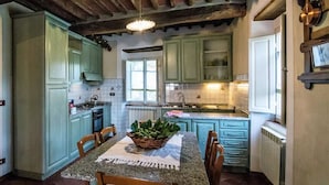 A kitchen with teal cabinets, a granite countertop, and a dining table with chairs. - Farmhouse with Farm in the hills of Barga: Casa Chioi (barga)