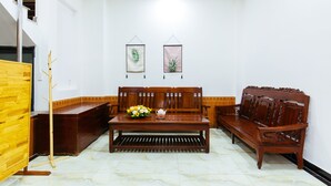 A room with a wooden bench, a small table with a teapot and flowers, and two framed botanical prints on the wall. - Hoa Cuc Phuong Hotel Di An - Binh Duong (Ho Chi Minh City)