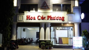 A hotel entrance with columns, a sign reading "Hoa Ciu Phuong", and several potted plants. - Hoa Cuc Phuong Hotel Di An - Binh Duong (Ho Chi Minh City)