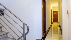 A hotel hallway with a marble floor, a wooden door with a number, and a metal staircase. - Hoa Cuc Phuong Hotel Di An - Binh Duong (Ho Chi Minh City)