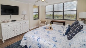 Un dormitorio con cama, televisor, cómoda y ventilador de techo.