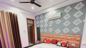 A modern bedroom with a bed, ceiling fan, air conditioning unit, and patterned wall. - Taj Street Hostel (Agra)