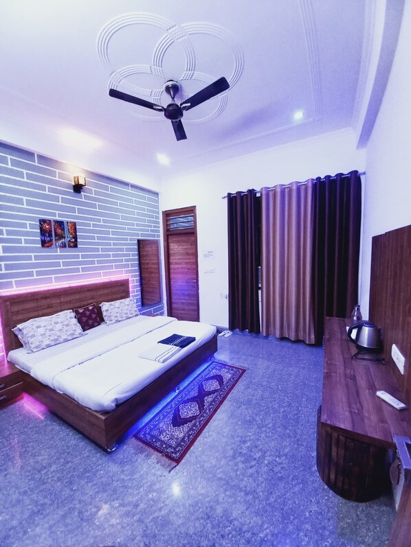 A modern bedroom with a bed, a desk, a ceiling fan, and a brick-patterned wall. - Taj Street Hostel (Agra)