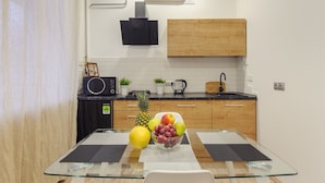 Una cocina moderna con armarios de madera, una campana extractora negra y una mesa de vidrio con un frutero.