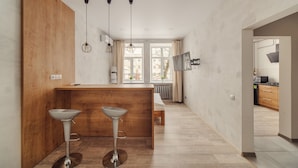 Una cocina moderna con una isla de madera, dos taburetes de bar, luces colgantes y vistas al comedor.