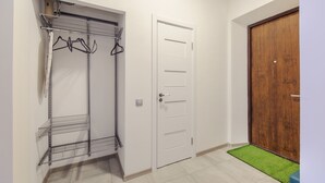 Una habitación con un armario blanco, una puerta de madera y un tapete verde.
