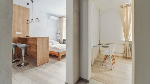 Un dormitorio moderno con una cama de madera, un escritorio pequeño y dos taburetes altos.