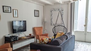 A living room with a sofa, a television, a radio, and a hanging chair. - Lovely space with terrace in the old town! (Catania)