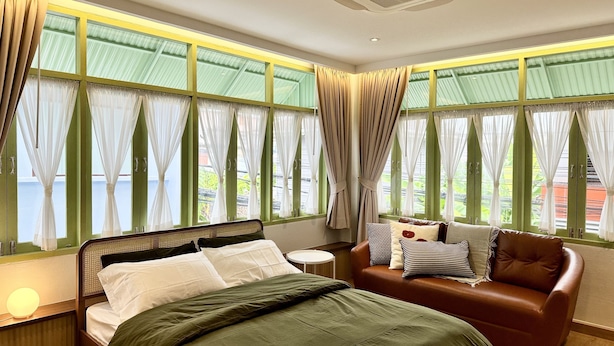 A hotel room with a bed, a sofa, and large windows with curtains. - The Tangerine Guesthouse (Bangkok)