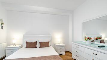 Un dormitorio con cama, mesitas de noche, cómoda y un espejo grande.