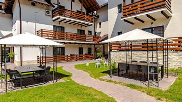 Um edifício moderno de vários andares, com áreas de estar ao ar livre, um terraço coberto e uma parede de pedra.