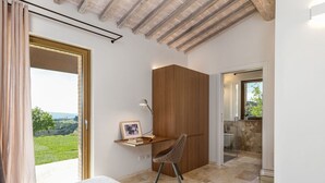 Quarto com cama, escrivaninha com cadeira, armário de madeira e banheiro com chuveiro e vaso sanitário.