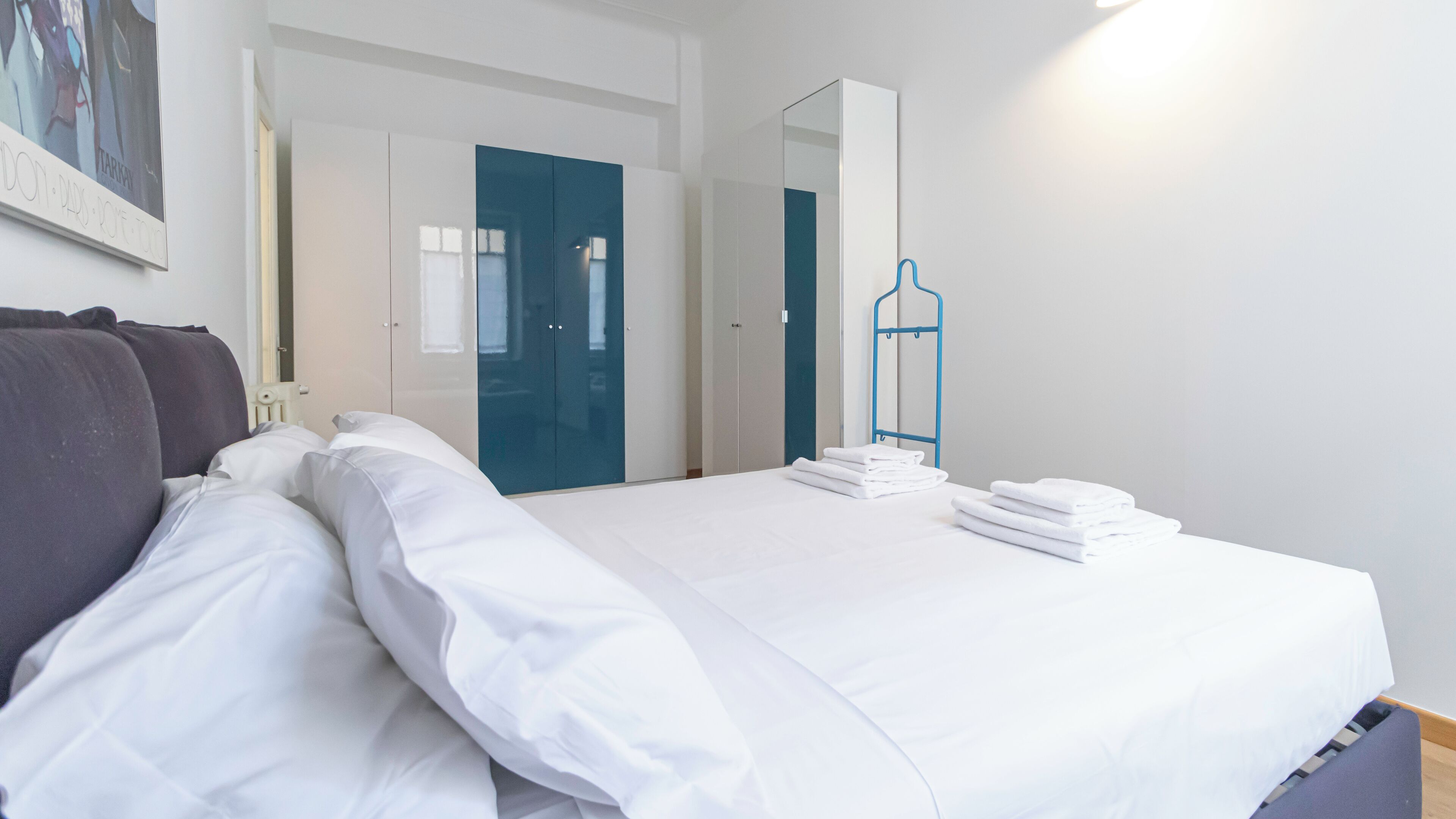 Quarto de hotel com cama, almofadas, guarda-roupa e espelho.