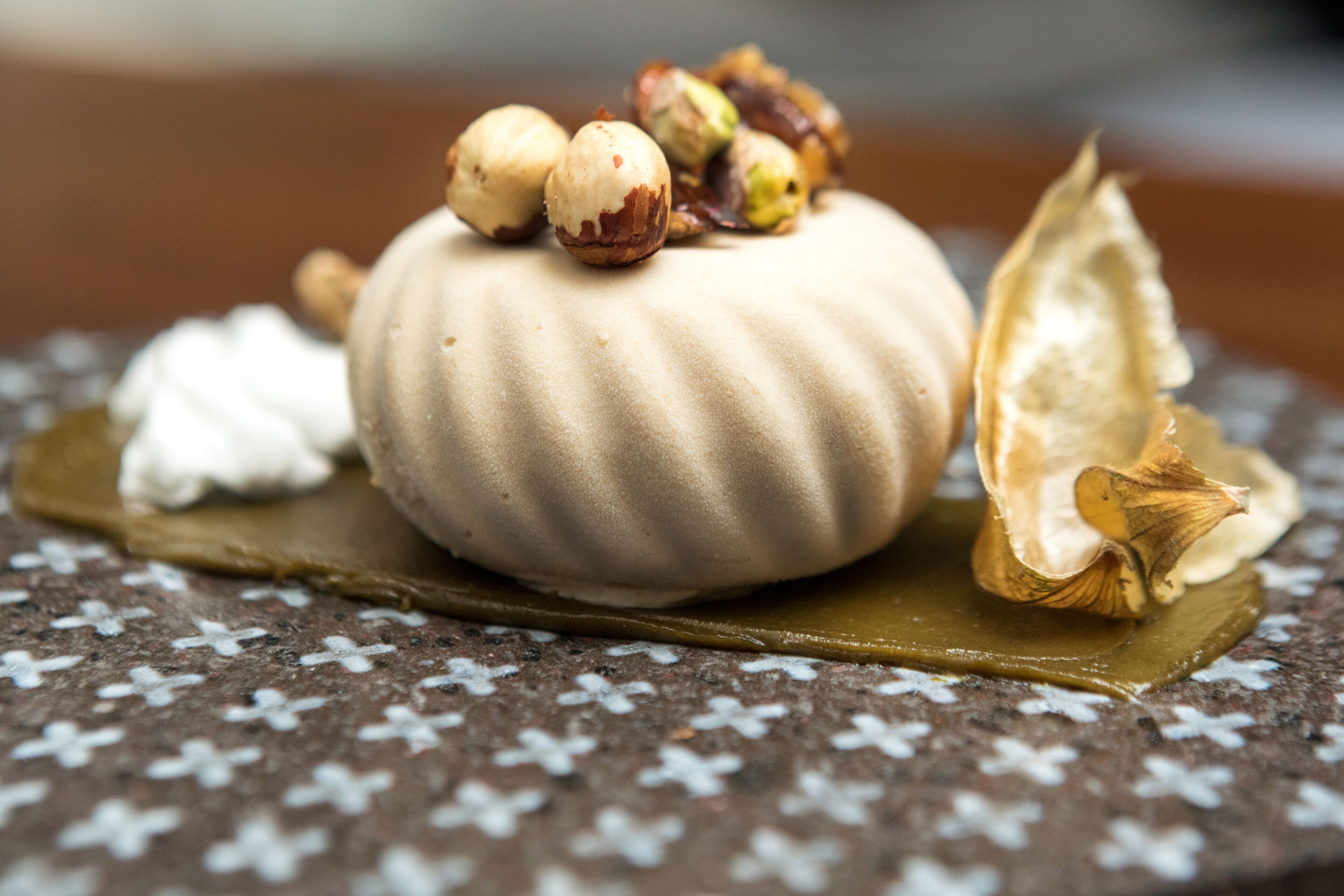 A dessert with a smooth, ridged surface, a halved fruit, and nuts on top.