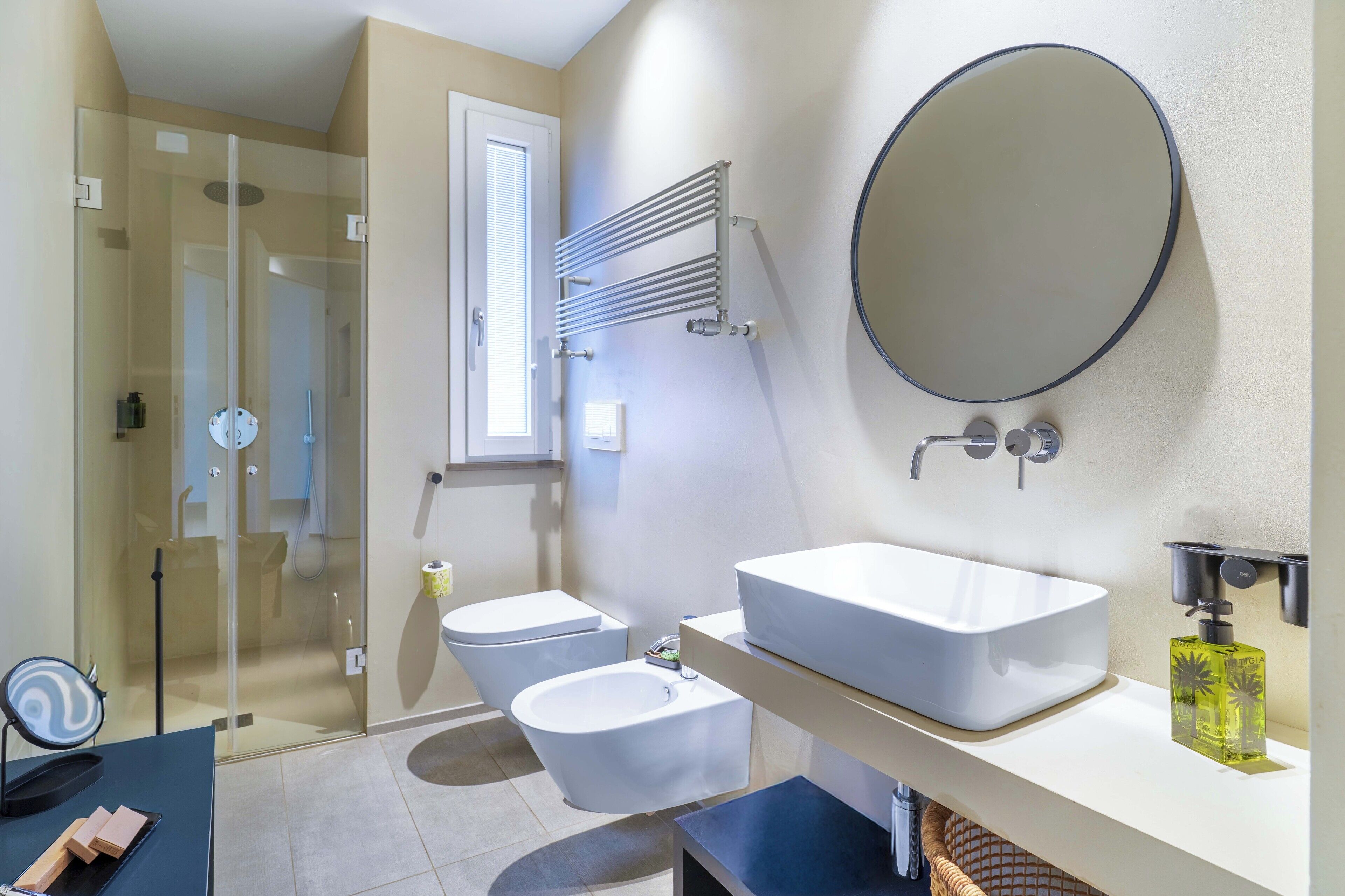 Une salle de bain moderne avec une douche à parois de verre, un lavabo blanc et un grand miroir.