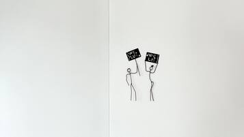Una pared blanca con dos figuras esquemáticas sosteniendo letreros que dicen "W.C. LUI" y "W.C. LEI".