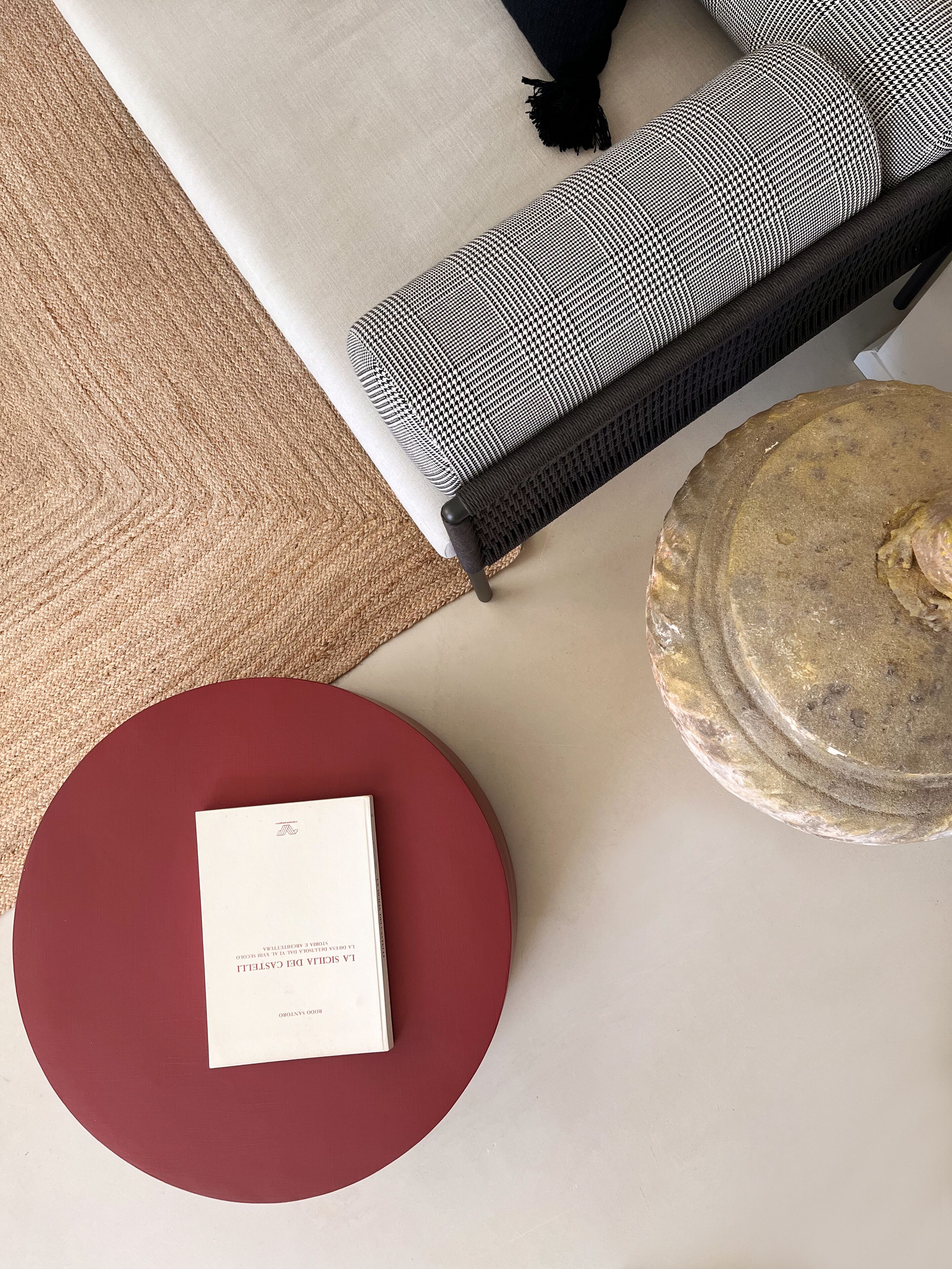 A room with a sofa, a round red table, and a stone table.
