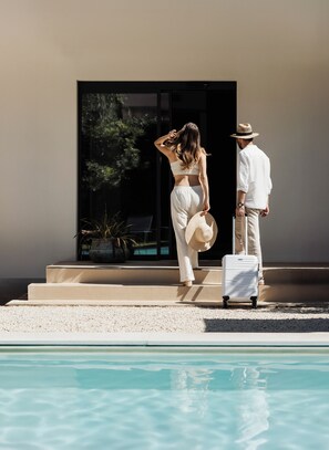 A poolside area with a modern building in the background, steps leading to the pool, and a suitcase on the ground. - Domìa Boutique Hotel e Cucina  (Palermo)