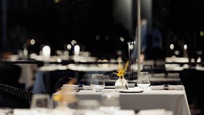 A dining table set with a vase of flowers, glasses, and a bottle of water. - Domìa Boutique Hotel e Cucina  (Palermo)