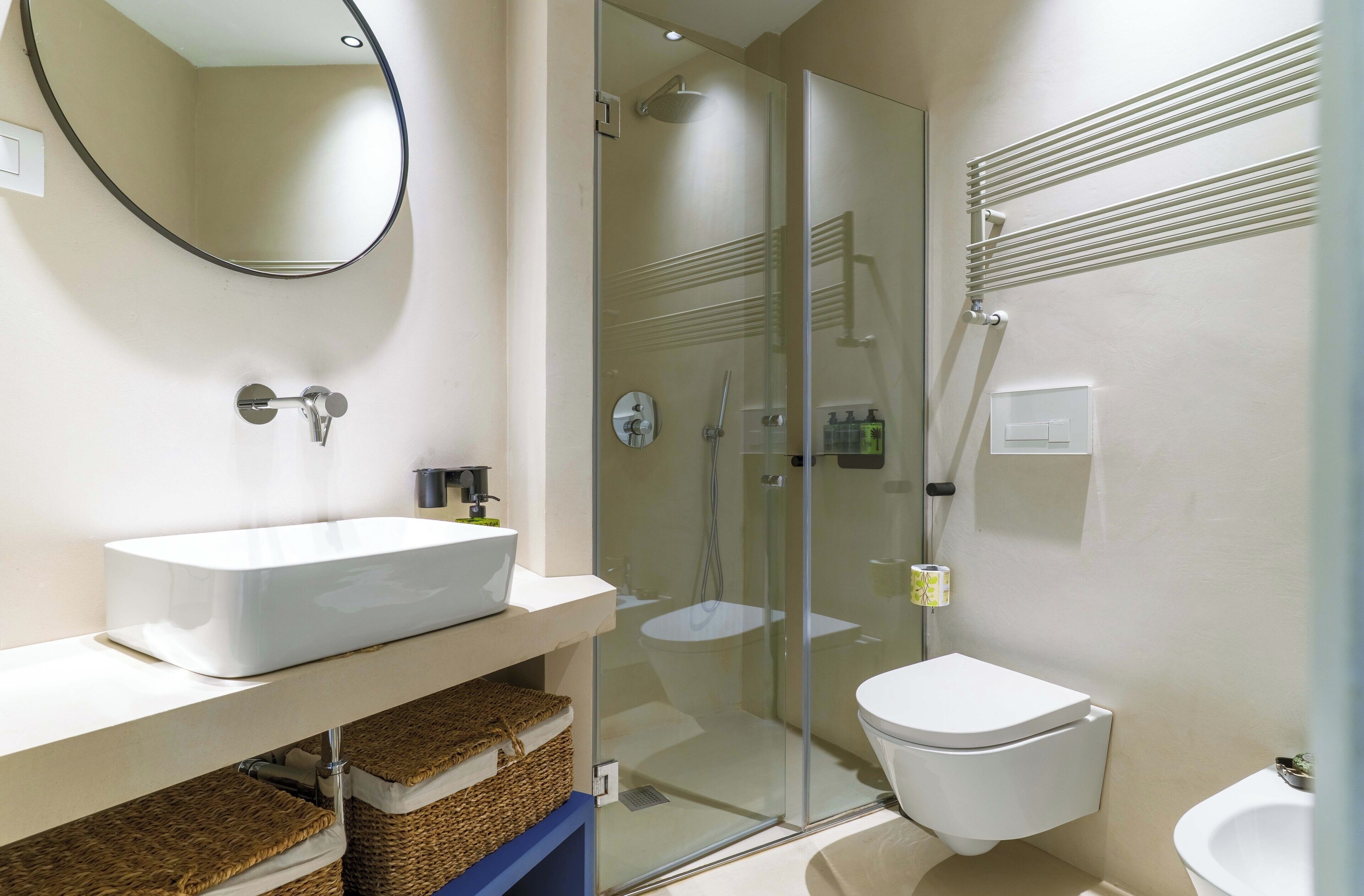 Un baño moderno con ducha envuelta en vidrio, un lavabo blanco y un inodoro.