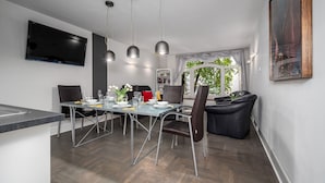 Un espace de salle à manger moderne avec une table en verre, des chaises en métal et des luminaires suspendus.