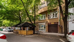 Une scène de rue avec un stand de restauration rapide, des voitures garées et un bâtiment doté d’une porte de garage.