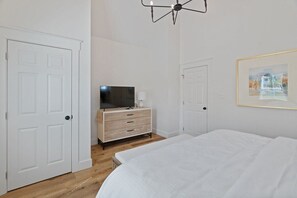 A bedroom with a bed, a dresser, a television, and a framed picture on the wall.