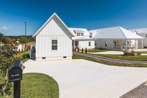 A residential area with white houses, a US mail mailbox, and a clear sky.