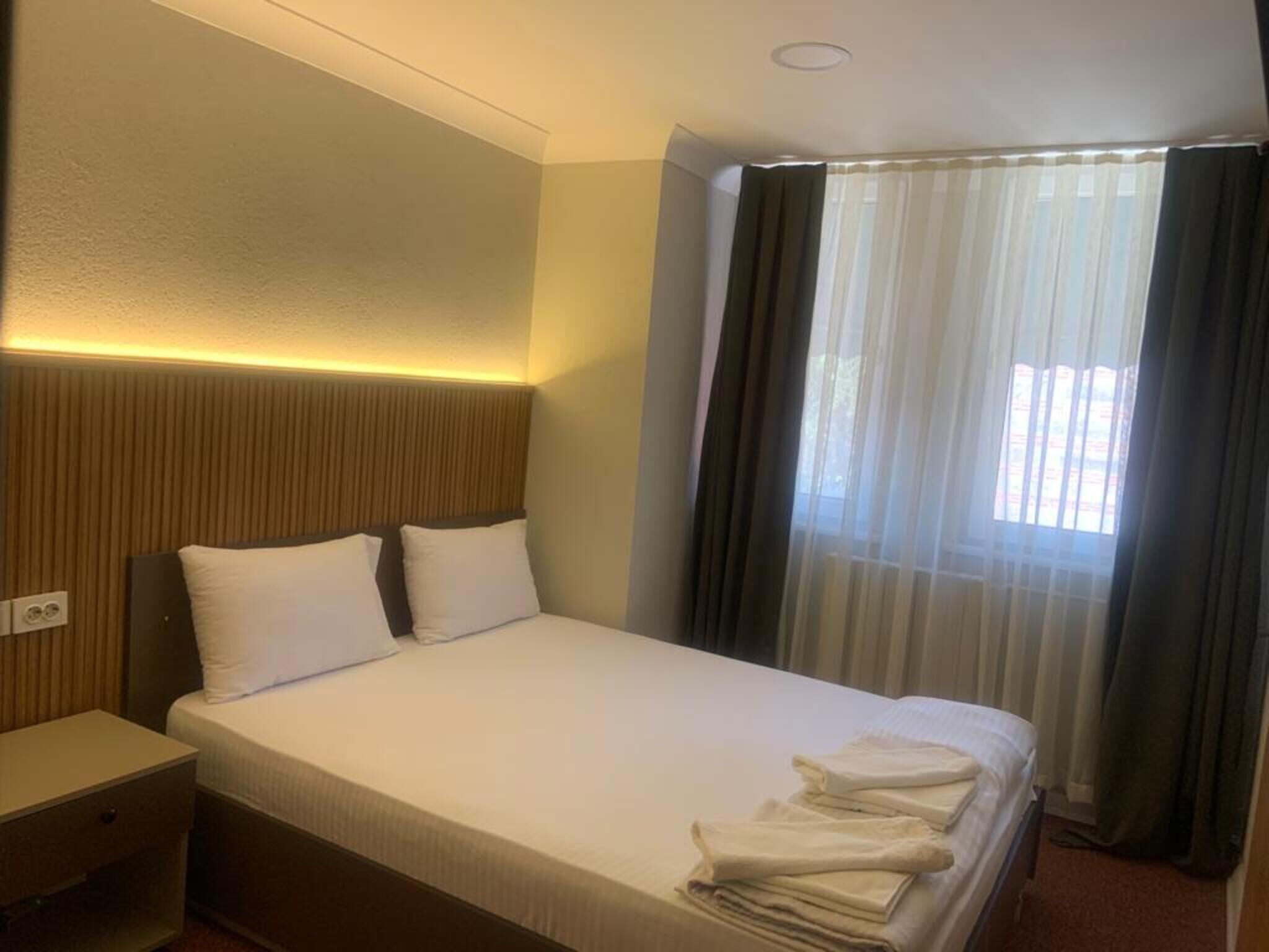 Une chambre d’hôtel avec un lit, une table de chevet et une fenêtre avec des rideaux.