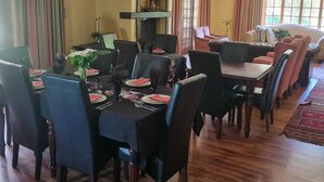 A dining area with a wooden table set for a meal, surrounded by chairs. - Deo Volente Country Estate  (Thabazimbi)