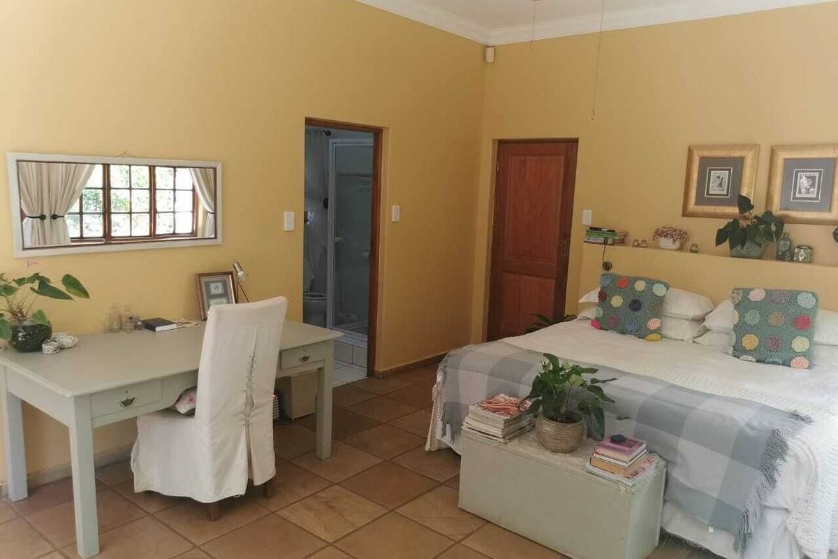 Ein Schlafzimmer mit Bett, Schreibtisch und Stuhl. Eine Tür führt in einen anderen Raum.