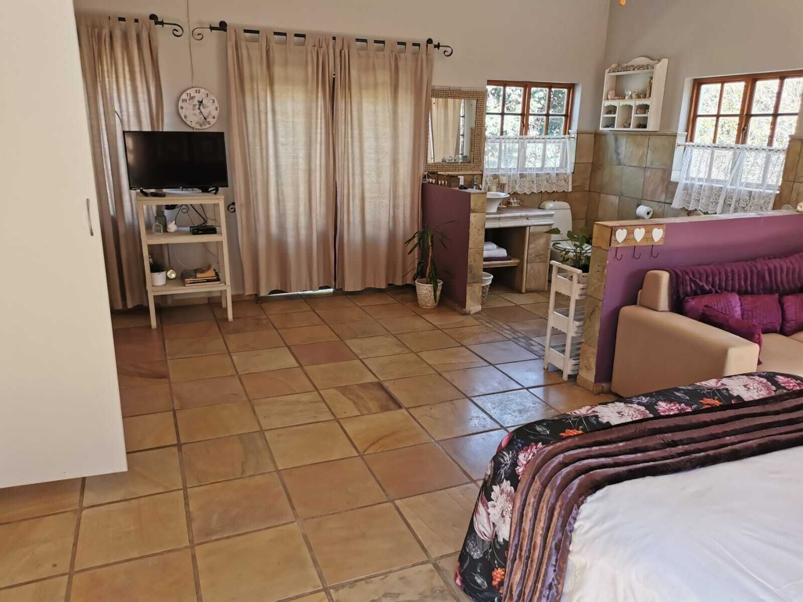 Un dormitorio con cama, escritorio, silla, televisión y baño.
