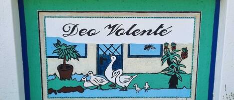 A colorful mural with the text "Deo Volente" and a scene of ducks and plants.