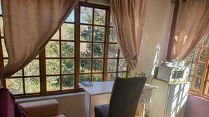 A room with a bed, a desk, a chair, a microwave, and a window with curtains. - Deo Volente Country Estate  (Thabazimbi)