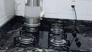 A kitchen with a gas stove, a kettle, and a tiled backsplash.