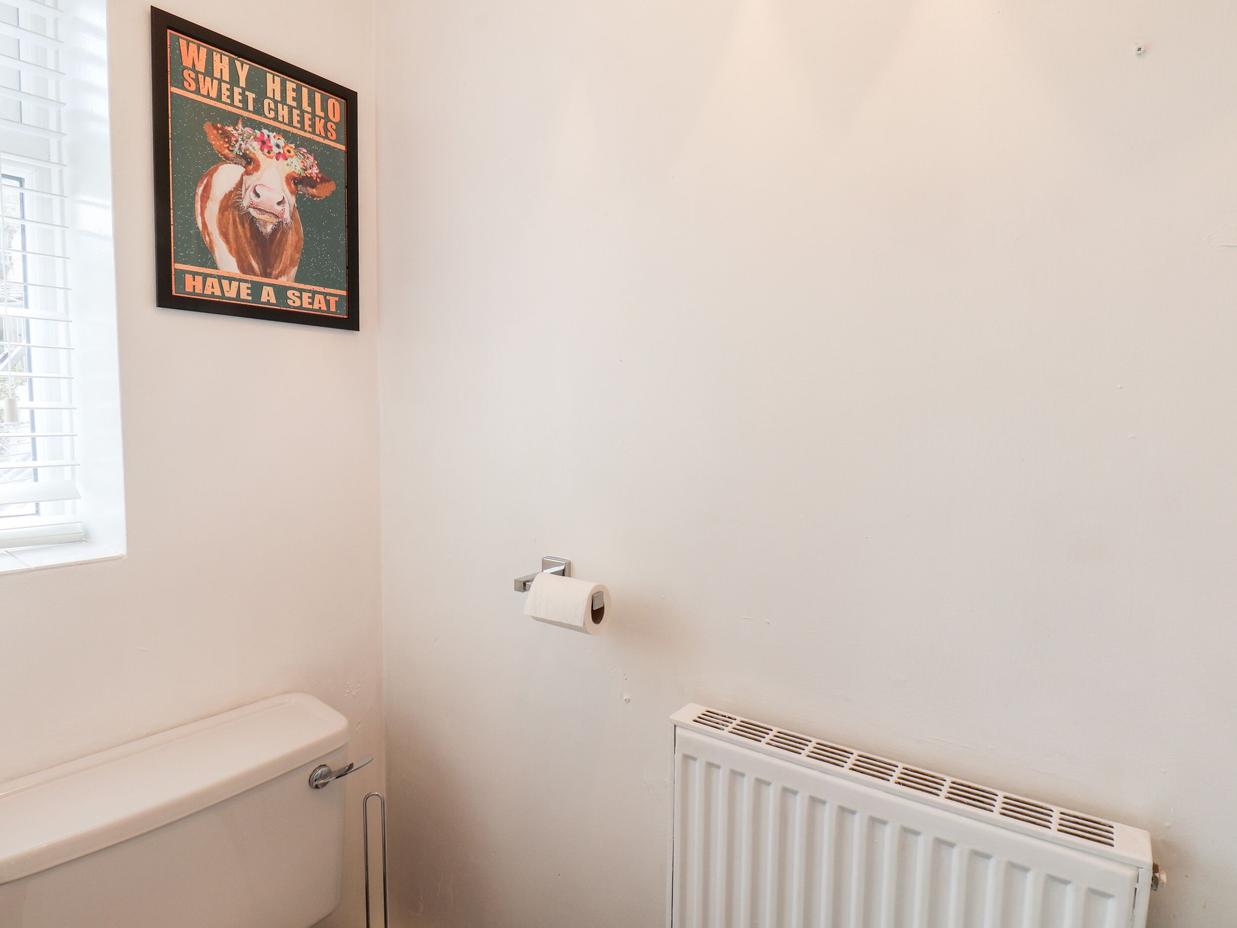 Et badeværelse med toilet, en radiator og et billede på væggen.